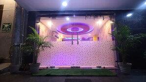 A hotel entrance with a purple-lit circular design, potted plants, and a green mat. - Jupiter Plaza (New Delhi)