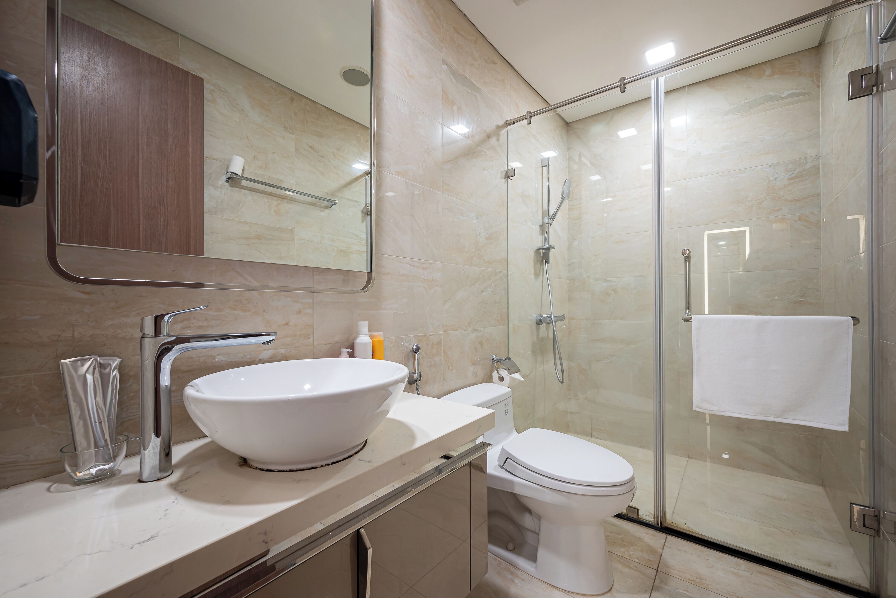 A modern bathroom with a large white sink, a glass shower enclosure, and a toilet.