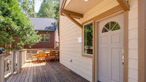 Una terraza de madera con un espacio de descanso techado y una puerta con ventana.