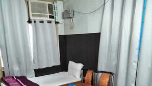 Et hotelværelse med en seng, et lille bord, en stol, en sofa og en aircondition.