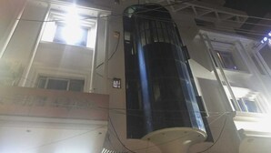 En bygning med en stor, cylindrisk struktur, muligvis en vandtank, samt en bygning med mange vinduer og et skilt med kinesiske tegn.