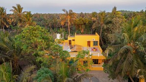Un bâtiment jaune entouré d’une végétation tropicale luxuriante.