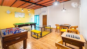 Une pièce équipée d’un baby-foot, d’une table de billard et d’un jeu d’échecs.
