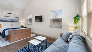 A modern living room with a bed, sofa, and TV.