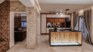Une cuisine moderne dotée d’un îlot central, de murs en pierre et d’un coin salon confortable avec une cheminée.