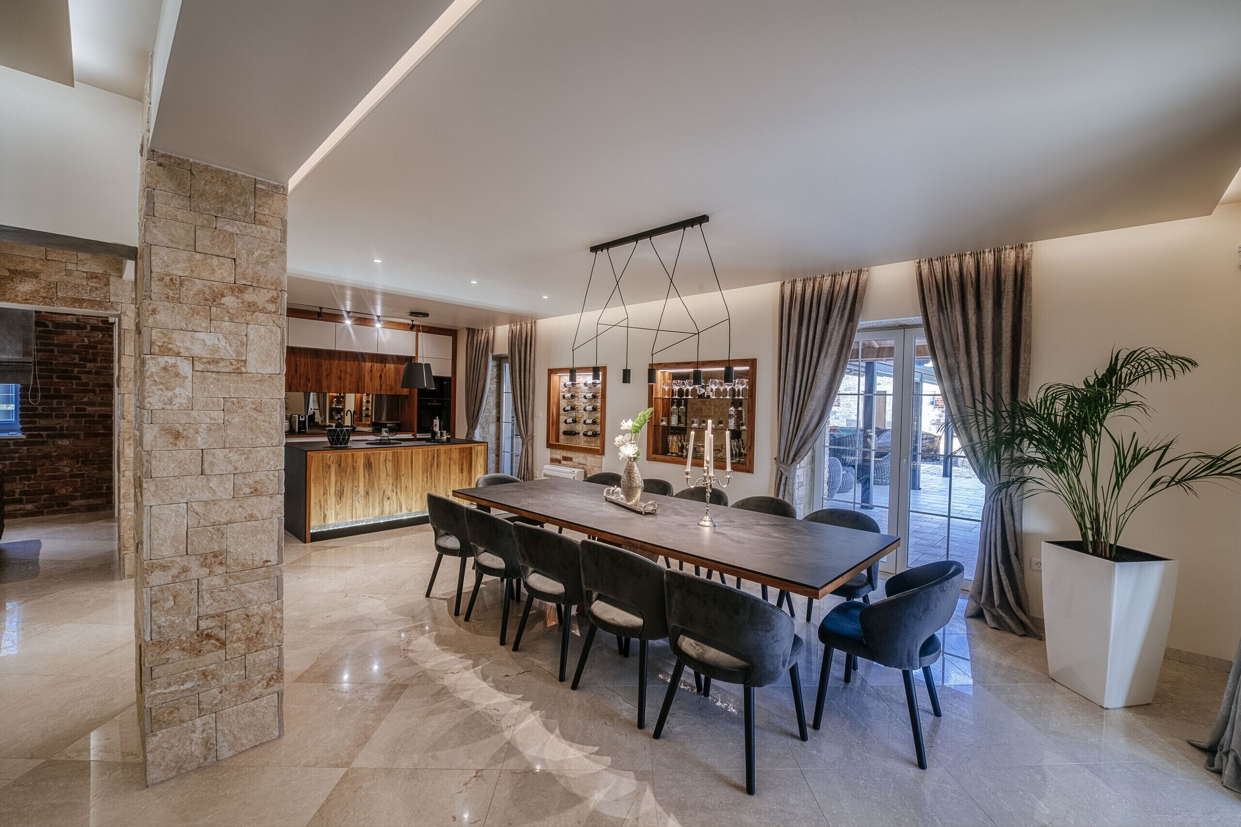 Un área de comedor moderna con una mesa larga, sillas oscuras y una planta en maceta.