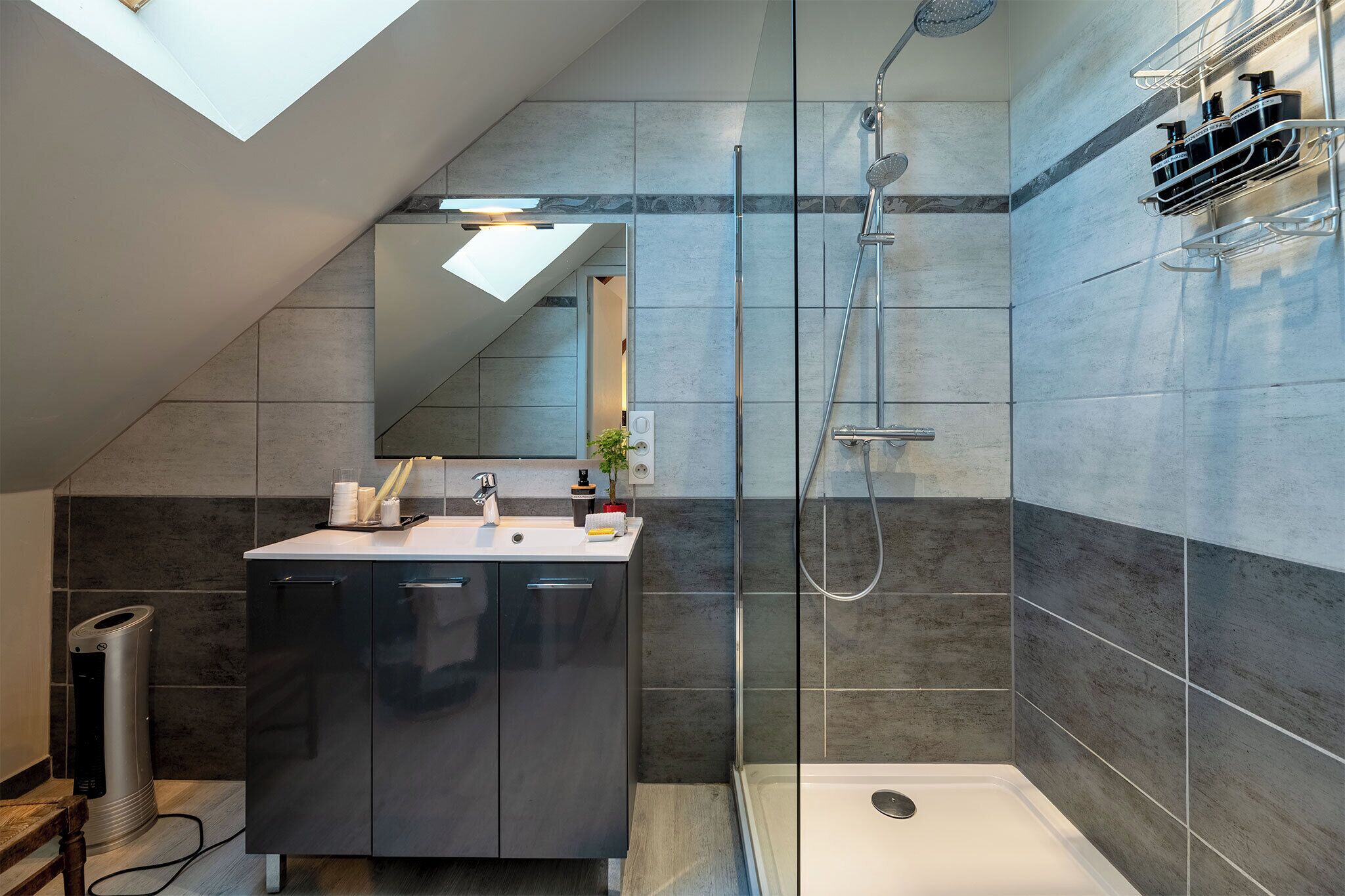 A modern bathroom with a shower, a sink, and a mirror.