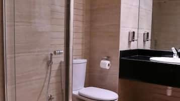 Un baño moderno con cabina de ducha de vidrio, un inodoro y un lavabo sobre encimera negra.