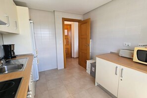 Eine kleine Küche mit Spüle, Herd, Mikrowelle und Schränken.