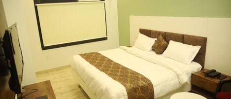 A hotel room with a bed, a bedside table with a phone, a small round table, and a TV on a stand.
