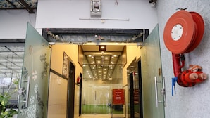 A hotel entrance with a glass door, a welcome sign, and a fire hose mounted on the wall. - Hotel Crown Royal (Kota)