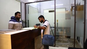 A reception area with a reception desk, a glass partition, and a sign above the desk. - Hotel Crown Royal (Kota)