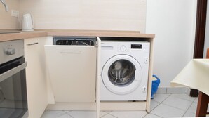 Eine kompakte Küche mit integriertem Waschmaschine, einer Kaffeemaschine und einer Mikrowelle.
