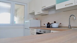 Eine moderne Küche mit weißen Schränken, einer Edelstahl-Spüle und einem Fenster.