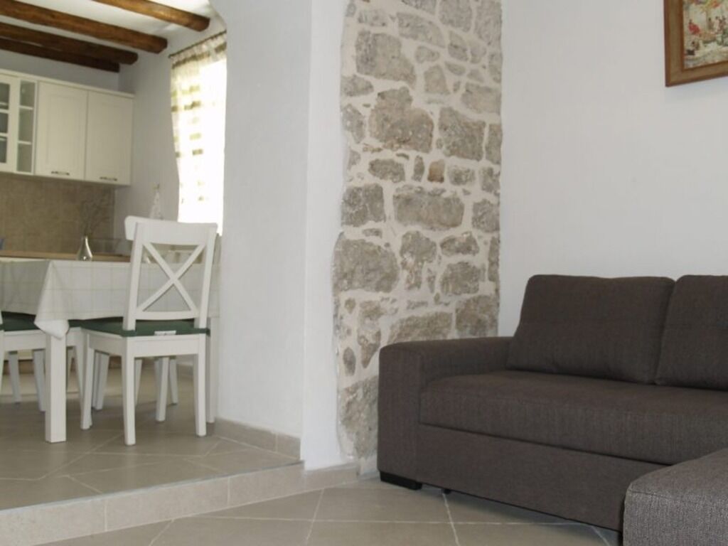 A dining area with a table and chairs, a stone wall, and a sofa.