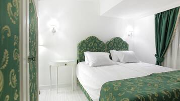 A hotel room with a bed, bedside table, and a nightstand.