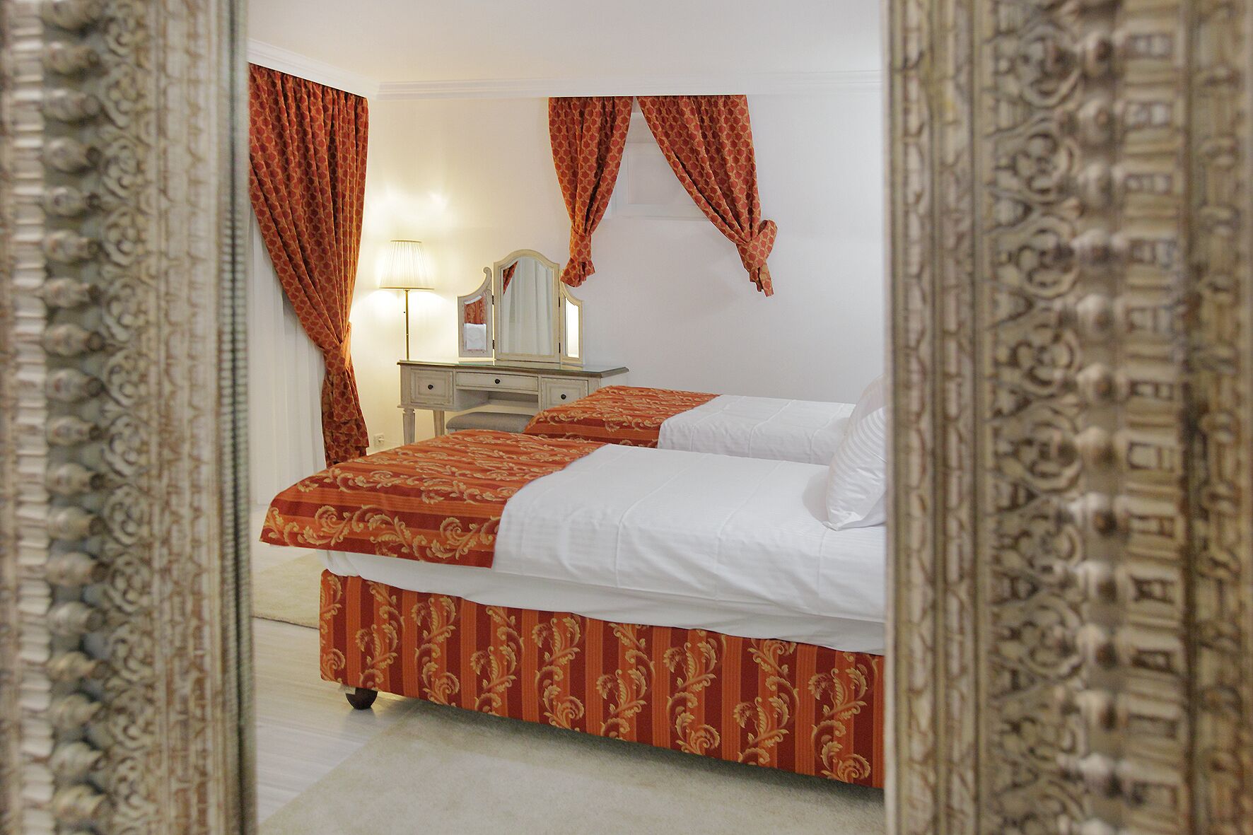 Een hotelkamer met een bed, een kaptafel, een spiegel en gordijnen.