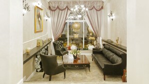 Un salon élégant, avec un canapé, des fauteuils, une table basse et un lustre.