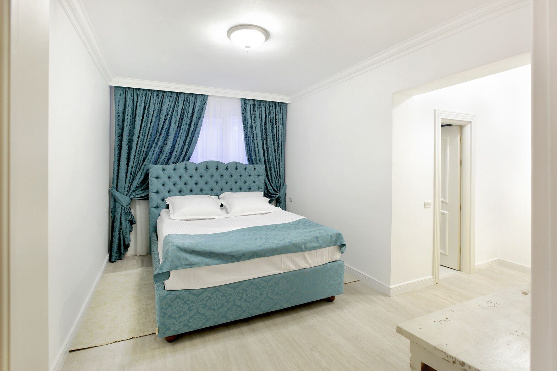 A bedroom with a bed, curtains, and a door.