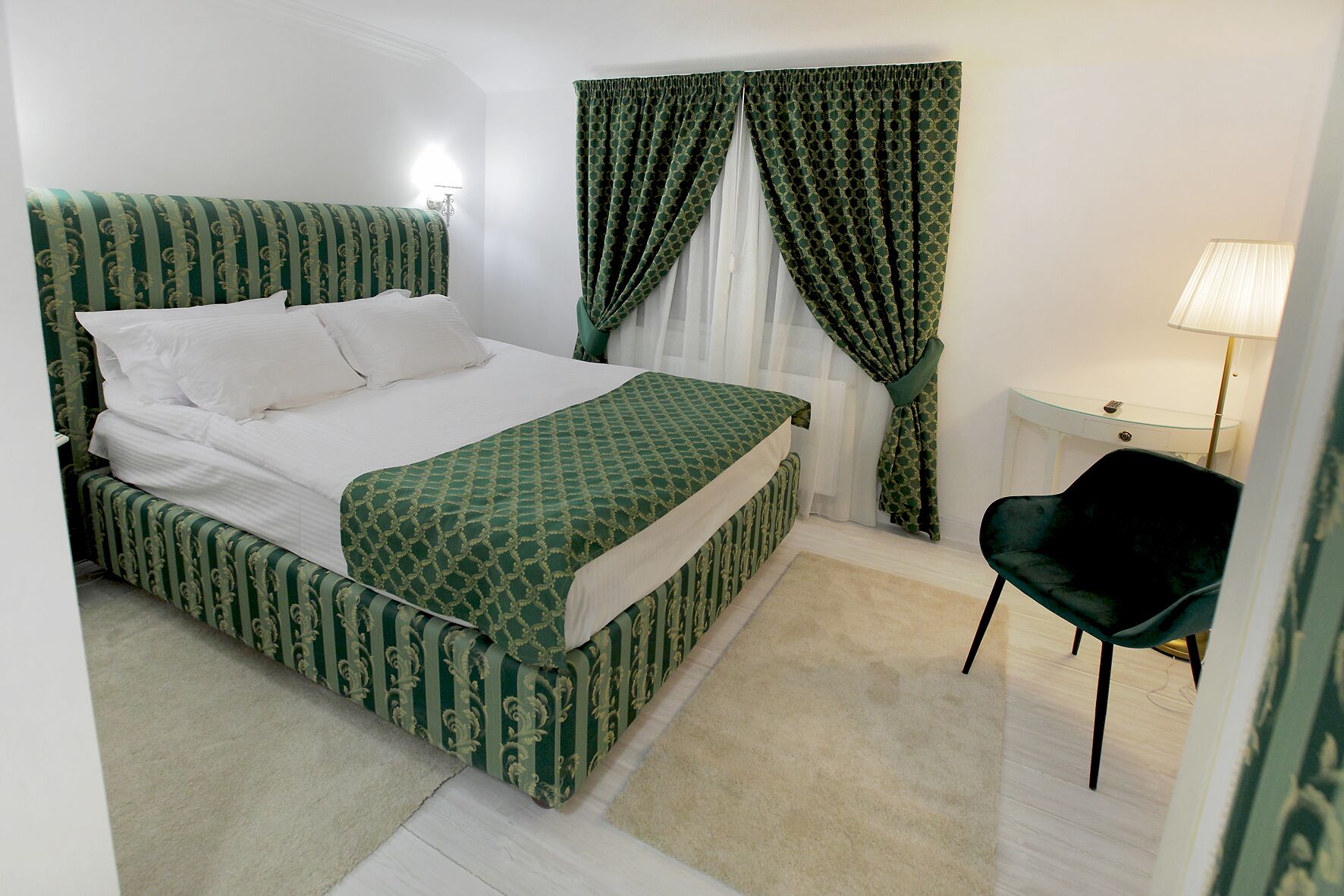 Un dormitorio ordenado con cama, una silla y una lámpara.