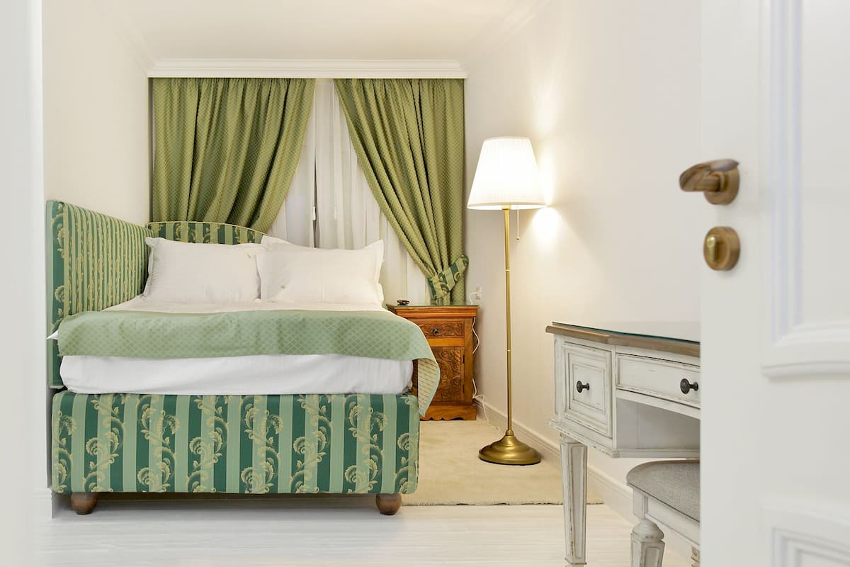 Een keurig opgemaakt slaapkamer met een bed, nachtkastje, lamp en een dressoir.