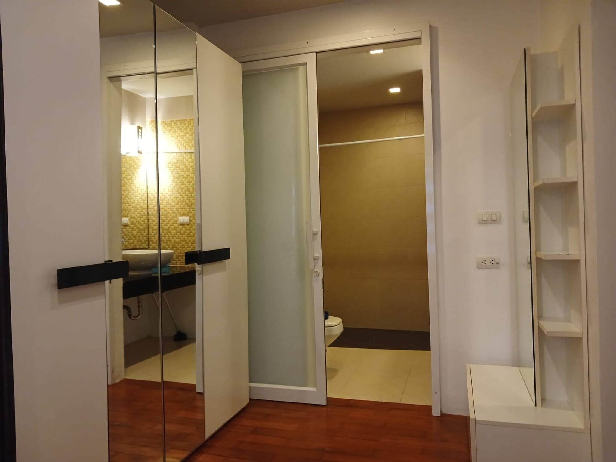 Un bagno moderno con box doccia in vetro, un WC e un lavandino con specchio.