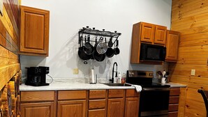 A compact kitchen with wooden cabinets, a stainless steel stove, and a microwave.