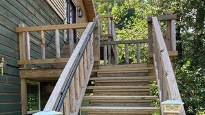 A wooden staircase with a railing, leading to a wooden deck.