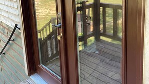 A wooden deck with a glass door leading to a grassy area.