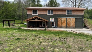 A two-story log cabin with a covered porch, a garage, and a bicycle parked outside.