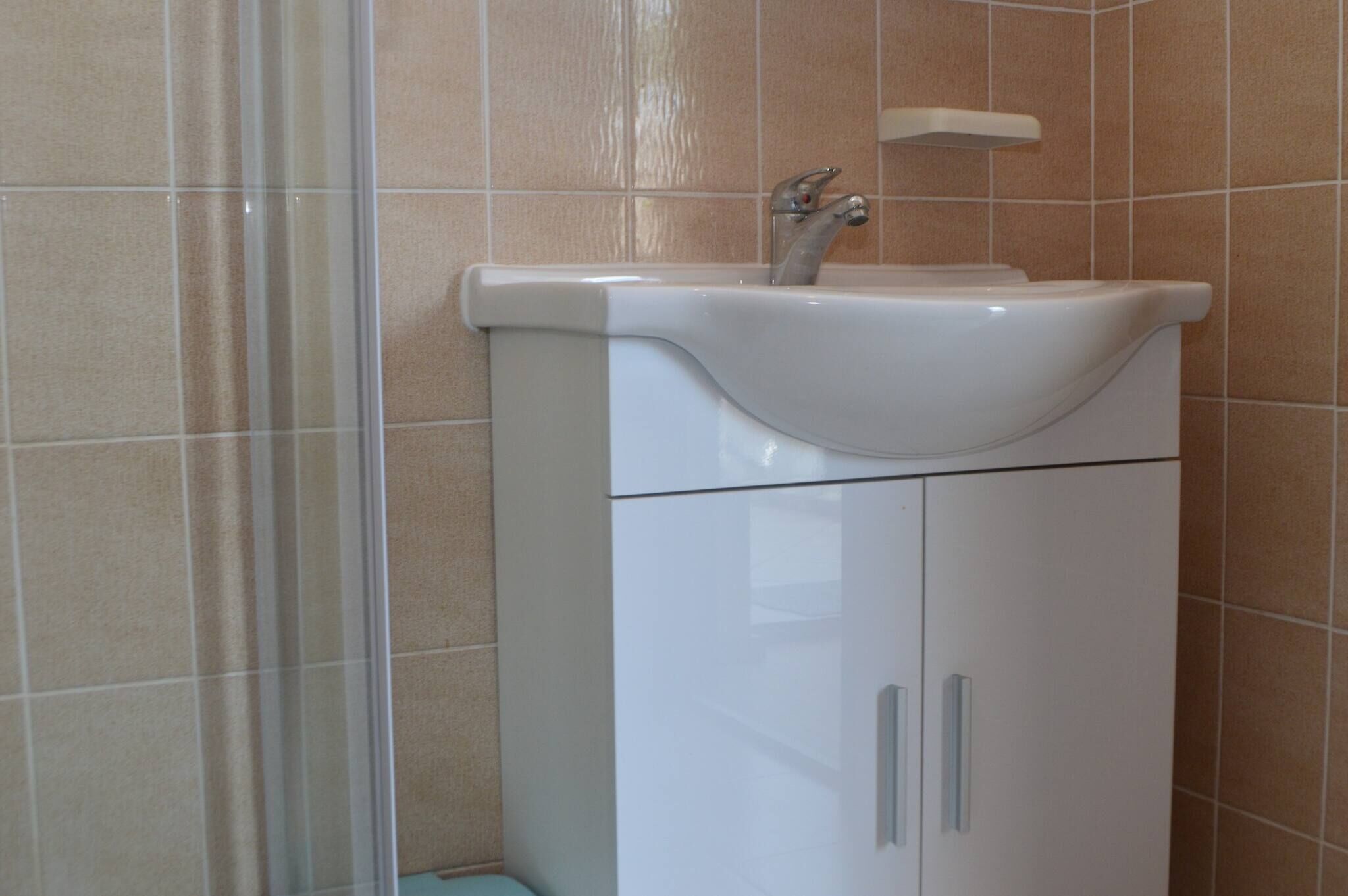 A bathroom with a white sink, a mirror, and a shower area.