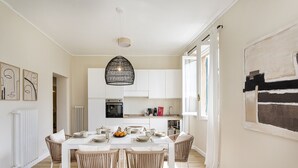 A modern kitchen with white cabinets, a dining table set with plates and cups, and wicker chairs. - Sea View Flat in Rapallo by Wonderful Italy (Rapallo)