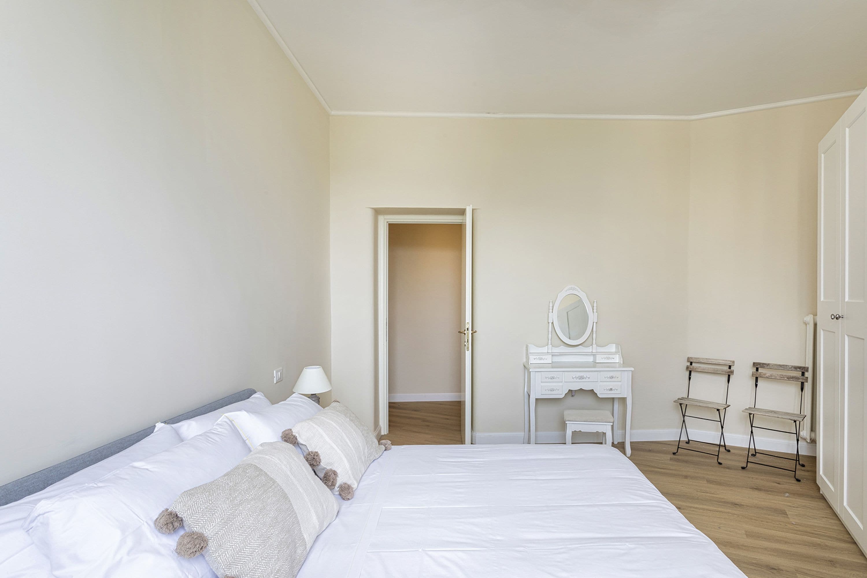 A bedroom with a bed, a dresser, a mirror, and two chairs.