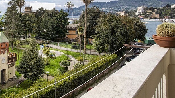 A balcony with a view of a coastal cityscape, including a body of water, mountains, and a variety of buildings. - Sea View Flat in Rapallo by Wonderful Italy (Rapallo)