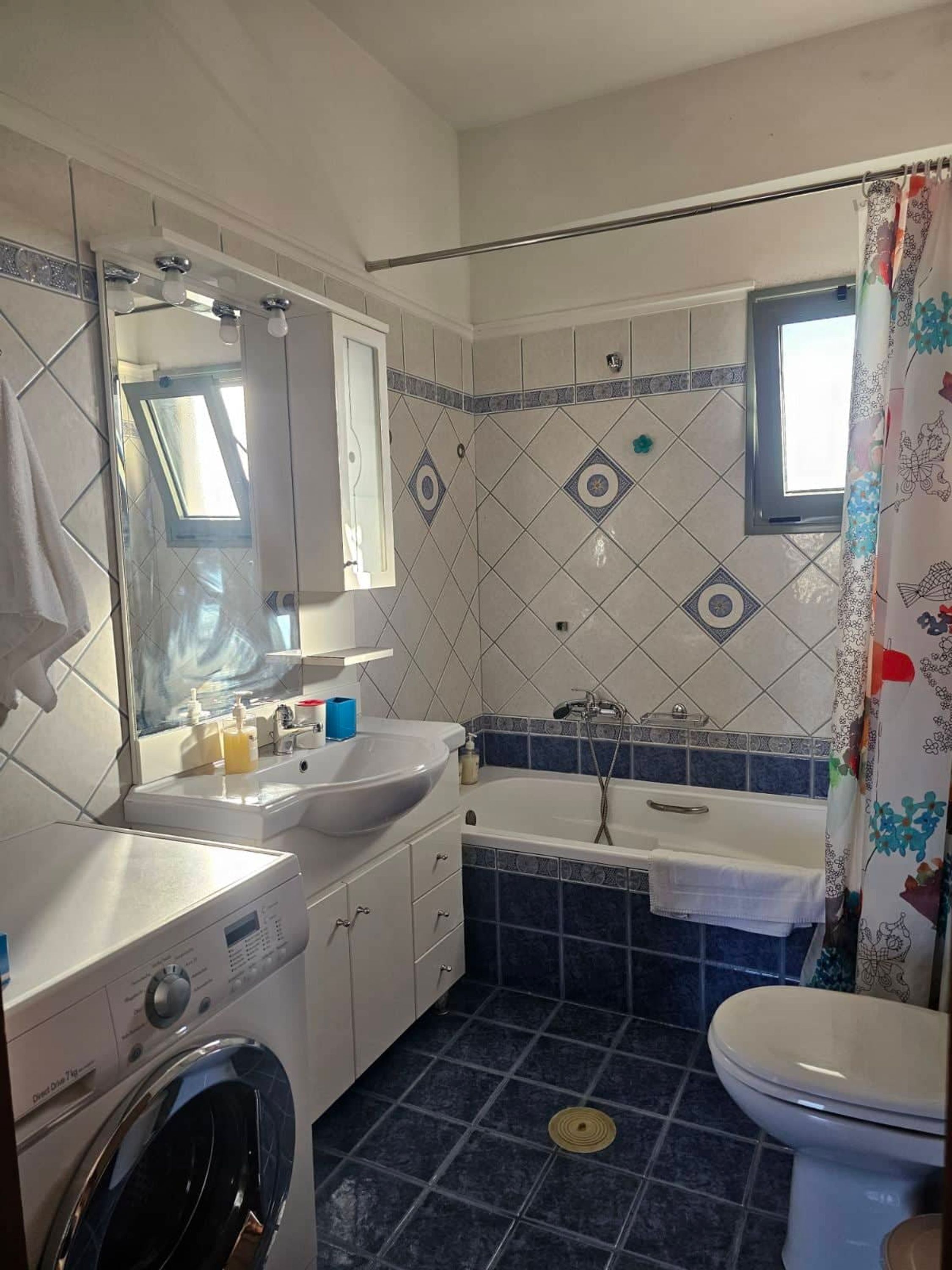Un baño con lavadora, dos lavamanos, bañera y retrete.