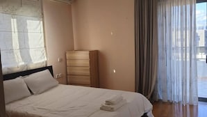 Ein Schlafzimmer mit Bett, Schminktisch, Klimaanlage und einem Vorhangfenster.