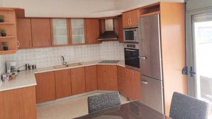 Eine moderne Küche mit Holzschränken, einem Edelstahlkühlschrank, einer Mikrowelle und einem Backofen.