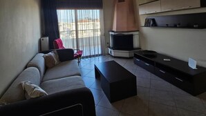 Ein Wohnzimmer mit einer Couch, einem Fernseher, einem Kamin und einem Balkon mit Blick.