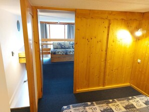 A room with a wooden door, a patterned rug, and a bed with a patterned bedspread. - 50m from ski slopes, Ground floor, balcony, tv, 30m², Les Arcs (Les Arcs)