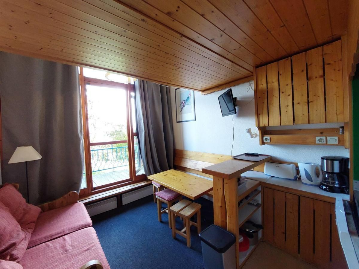 Una habitación acogedora con techo de madera, una mesa de comedor, un sofá y una cocina con cafetera.