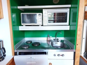 A compact kitchenette with a microwave, oven, sink, and stove. - 50m from ski slopes, Ground floor, balcony, tv, 30m², Les Arcs (Les Arcs)