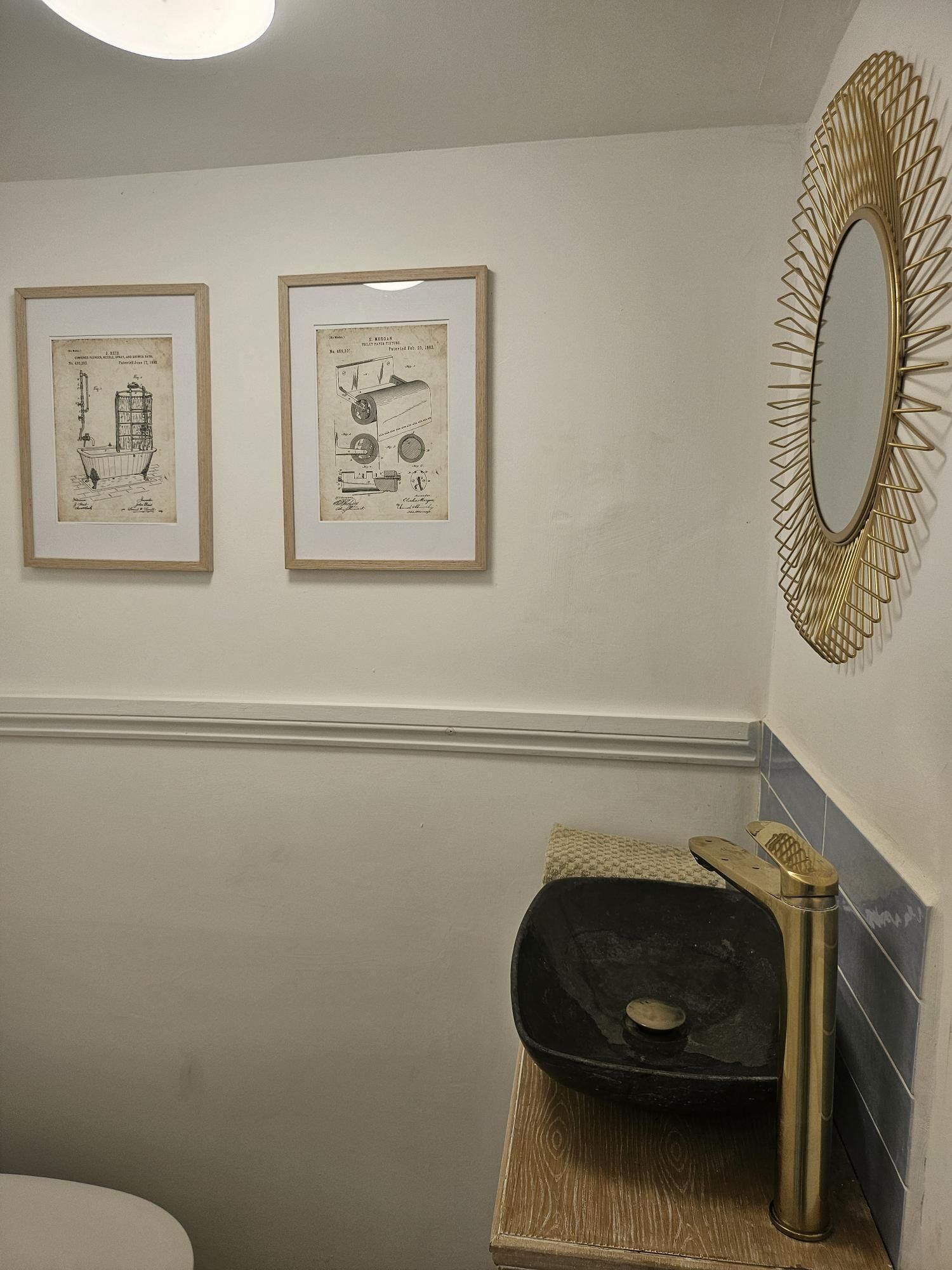 Un baño con lavamanos, espejo y dos dibujos enmarcados en la pared.