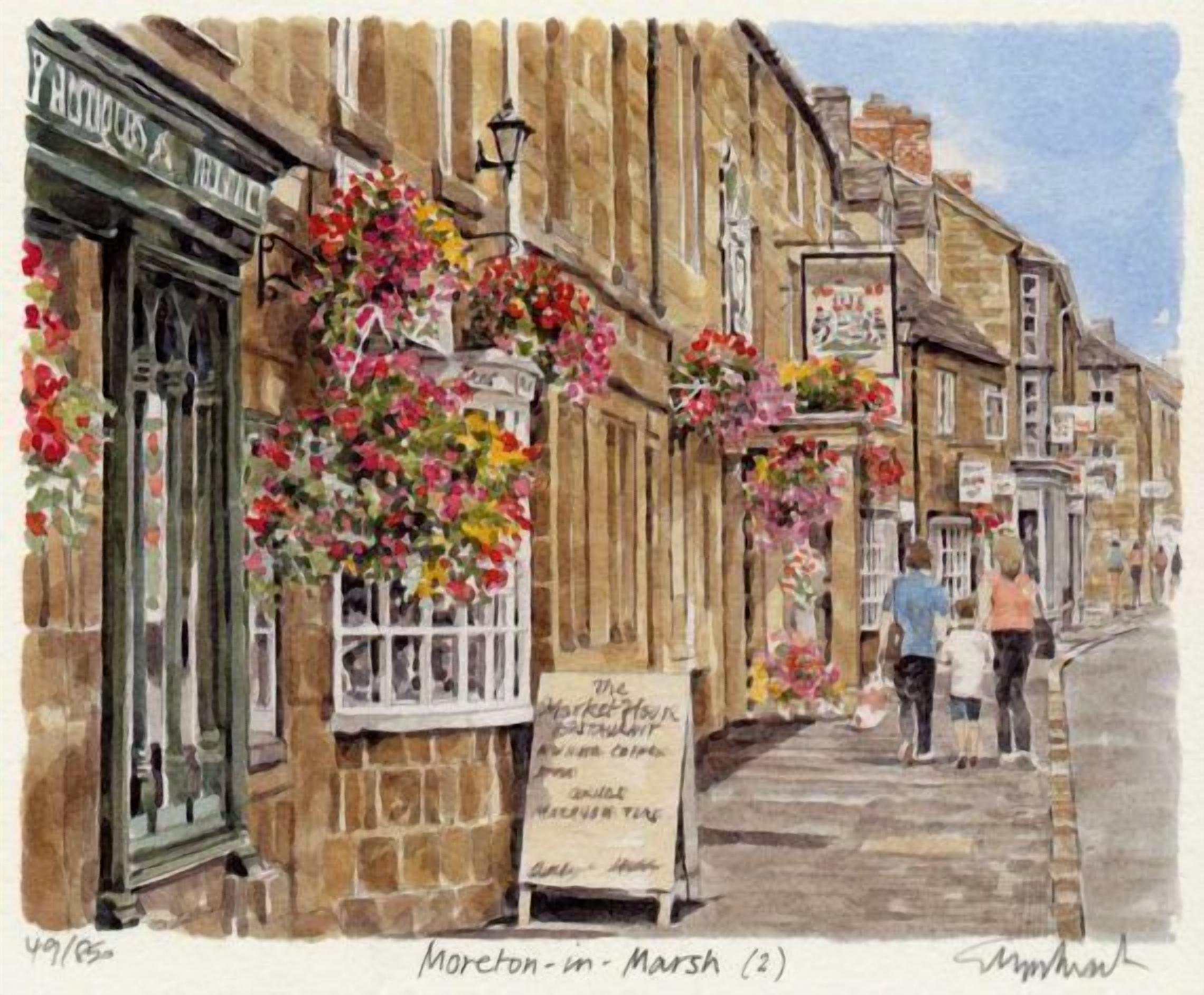A street scene with buildings, a signboard, and hanging flower baskets.