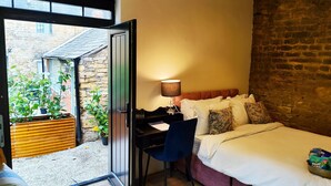 A bedroom with a bed, a desk, and a chair. There is a window with a view of a courtyard and a brick wall. - Cotswold Bankview (Moreton-in-Marsh)