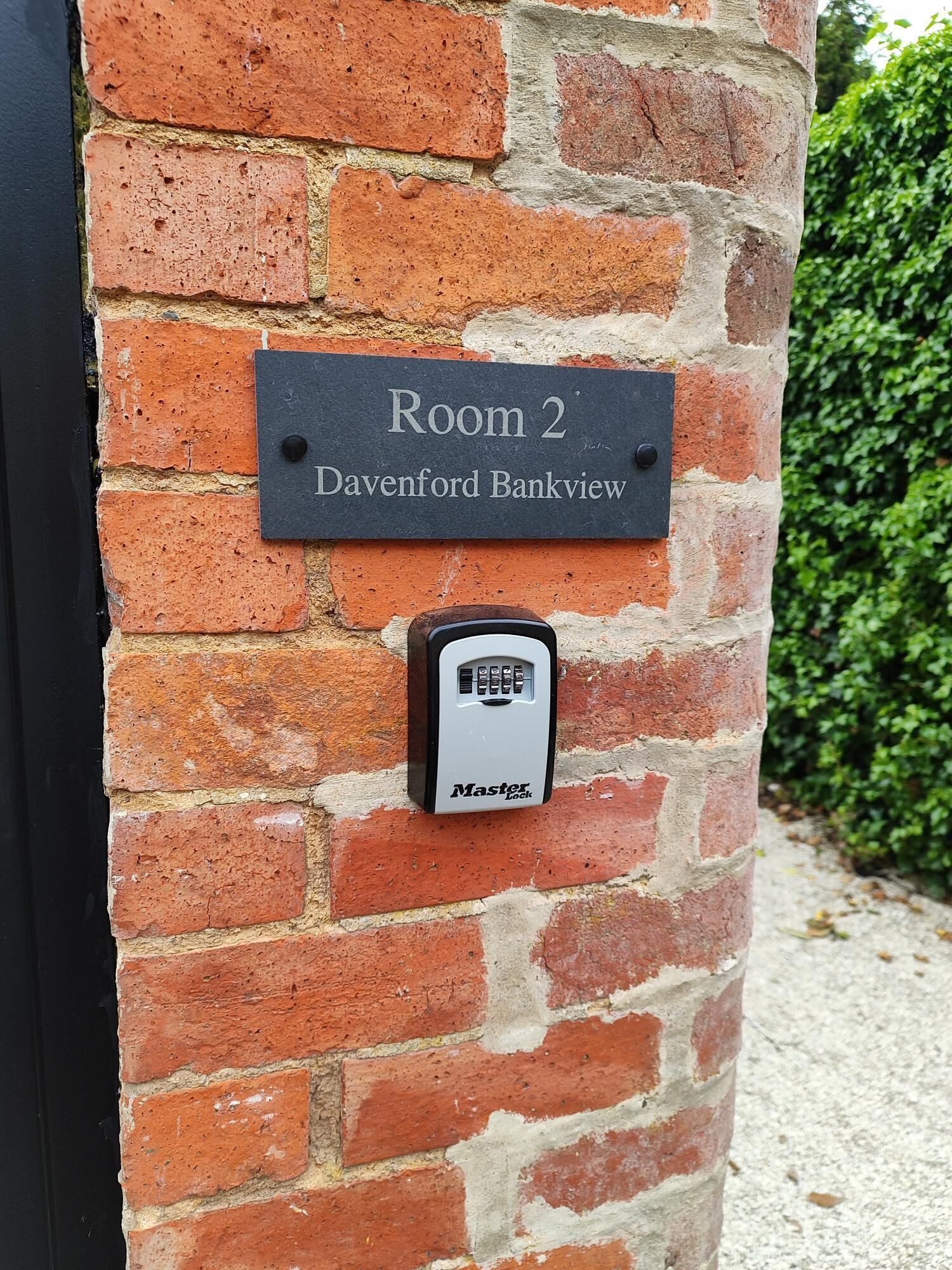 Een bakstenen muur met een bord waarop 'Kamer 2' en 'Davenford Bankview' staat.