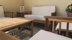 Een gezellig patio met een houten tafel, een witte bank en een kleine plant in een pot.
