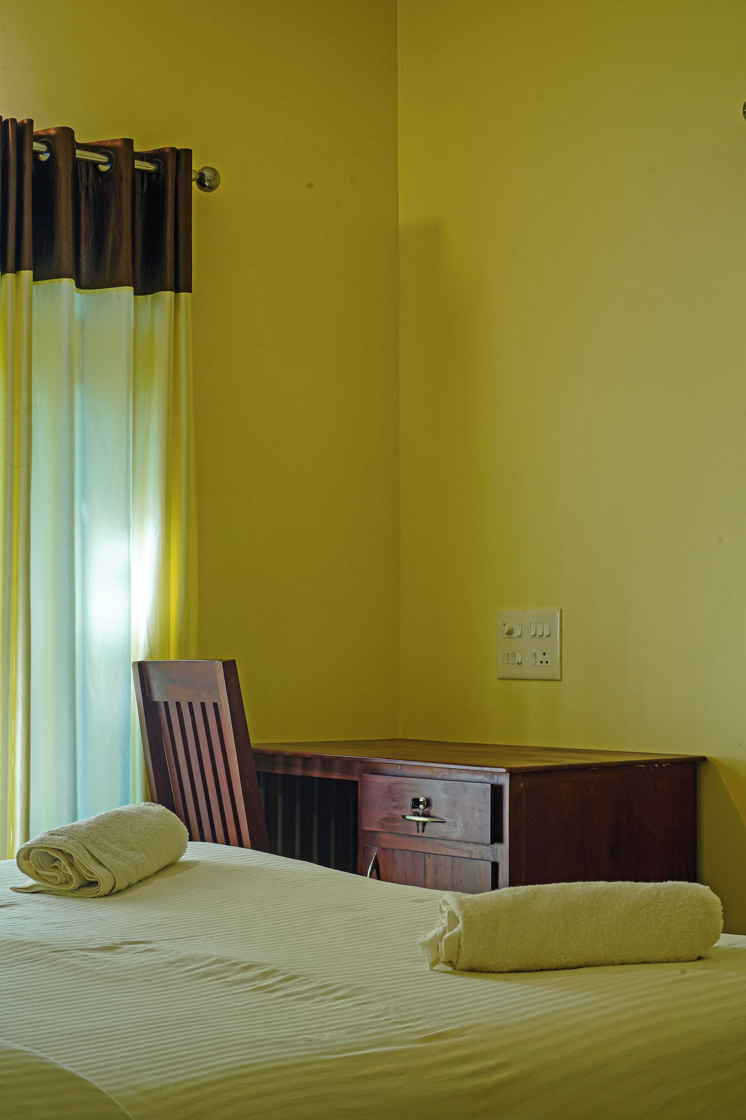 Una habitación con una cama, un escritorio de madera y una silla.