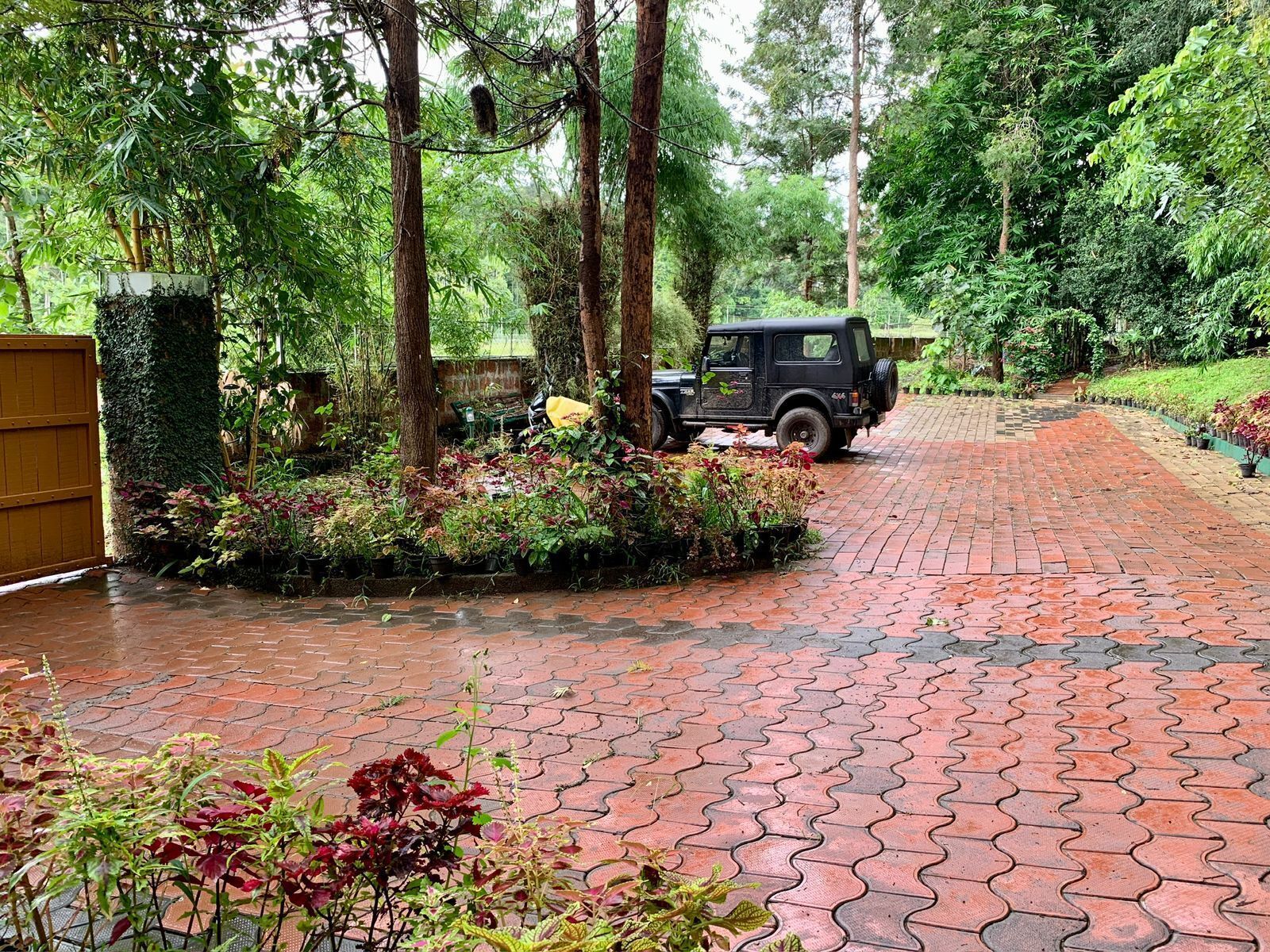 Ein gepflasterter Weg schlängelt sich durch einen üppigen Garten, ein geparktes Fahrzeug ist dort zu sehen.