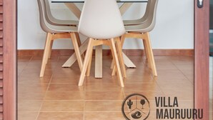 A dining area with a glass table and wooden chairs, a hanging pendant light, and a tiled floor. - Villa Mauruuru 10 Minutes Walking From Marina Rubicón, Heated Pool&bbq (CN)