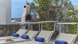 A rooftop lounge area with lounge chairs, a stone wall, and a chimney. - Villa Mauruuru 10 Minutes Walking From Marina Rubicón, Heated Pool&bbq (CN)